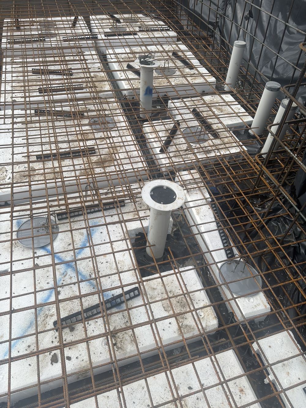 Slab mesh hard against service pipes without the 25 mm clearance, found during a slab pre-pour inspection in Pennant Hills
